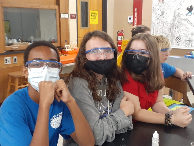 Three students wearing safety goggles